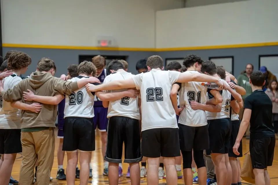 Basketball players gathered shoulder-to-shoulder in a team huddle